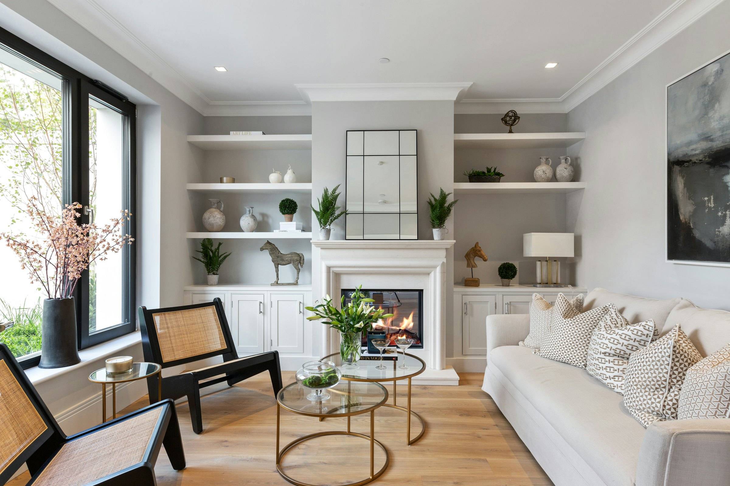 Light sitting room with a fireplace, built-in shelves and black-framed windows