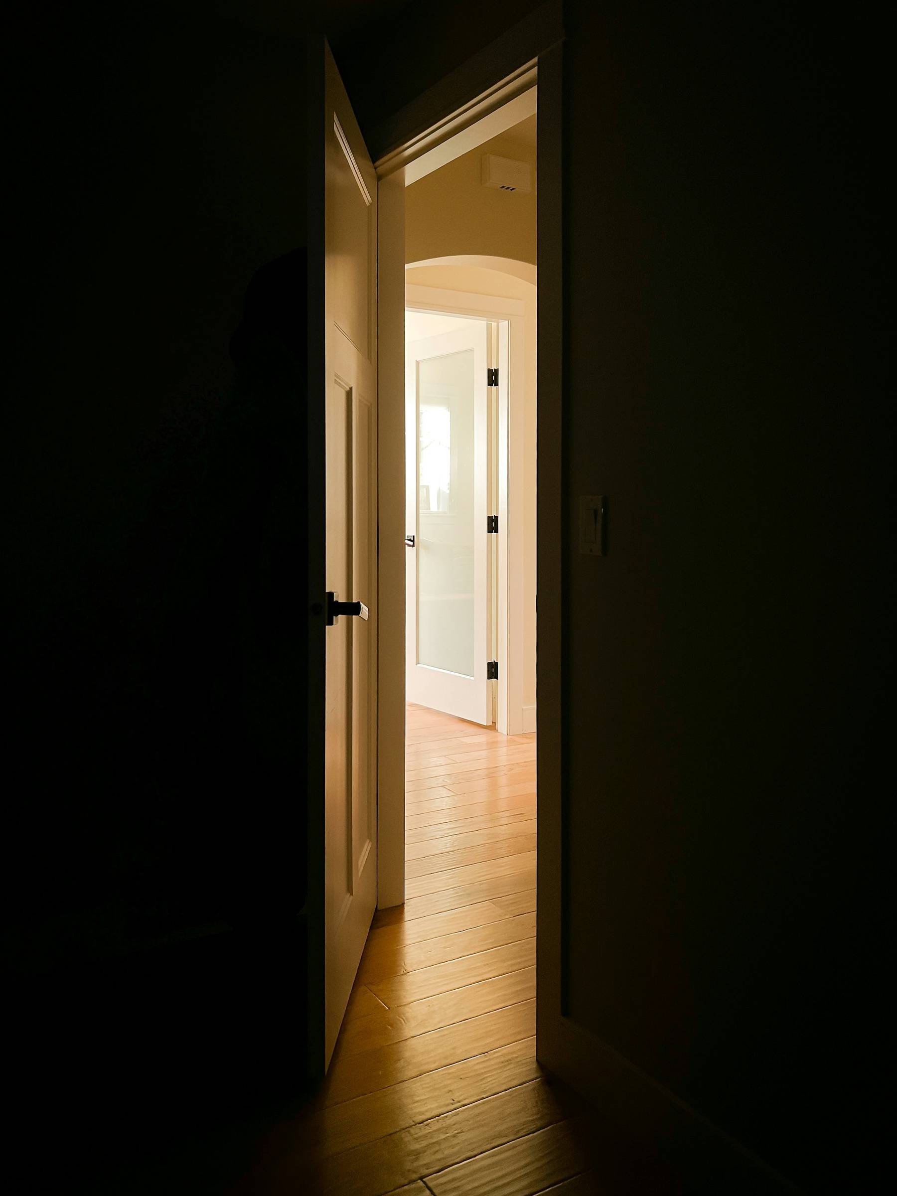 Open door letting light into a dark hallway