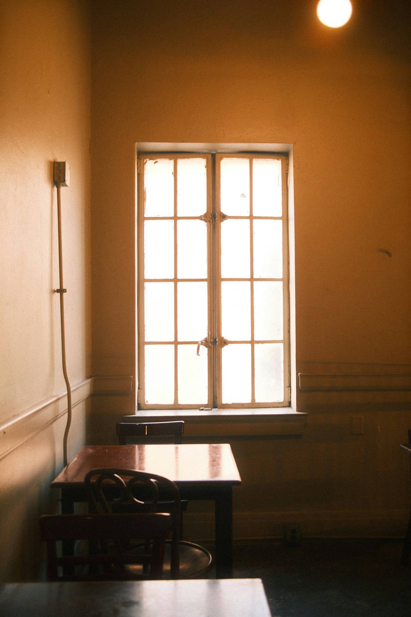 Sunlit room with a table and chairs beside a tall paned window